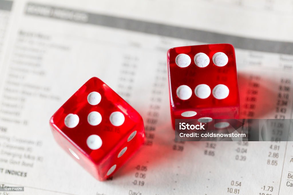 Close up macro color image depicting a pair of red dice on top of stock market data, indicating the potential risk of gambling on the stock exchange when buying stocks and shares. Room for copy space.