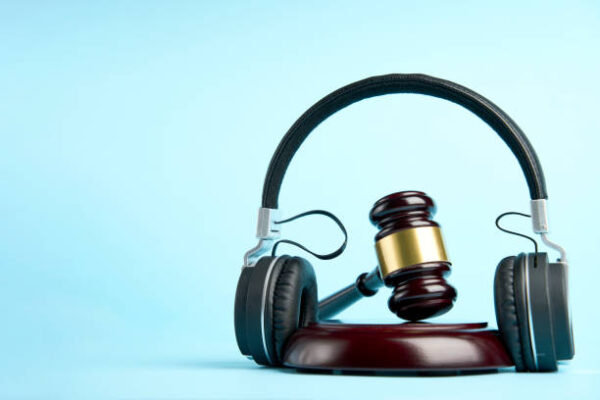 Music copyright law concept. Headphones and judge gavel background with copy-space. Music piracy and owners rights